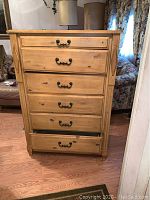 Front view of the five-drawer wooden chest with metal handles.