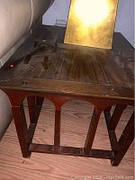 Close-up of one end table showing wood surface with nicks and geometric leg design