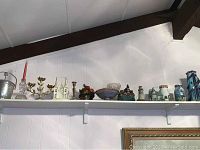 Wide shot showing all items on the upper white shelf including candlesticks, lighthouses, ice bucket, ceramic bowls, and decor items.