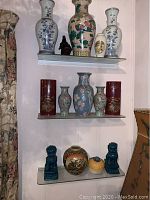 Three glass shelves displaying various vases and figurines