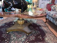 Coffee table with black dog sculpture and other decorative items on top, showing marble surface and wooden base with gold accents