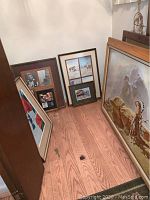 Initial grouping showing four framed art pieces leaning on floor beneath a dream catcher hanging on the wall