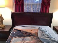 The front view of the dark wooden headboard attached behind the bed, showing the decorative panels and curved top.