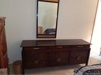 Full view of the nine drawer dresser with matching mirror hung above it, showing dark wood finish and drawer layout.