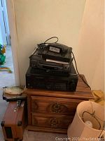 Stacked Sony receiver with Curtis Mathes VCR and other items on a wooden cabinet.