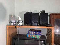 Advent speakers and subwoofer alongside Mason Ware computer speakers and vintage video games placed on a wooden TV stand.