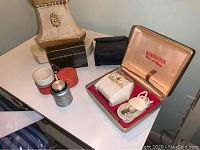 Remington razor in hinged case displayed alongside lighter box and black pouch