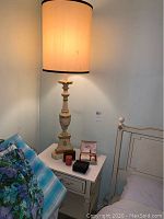 Pair of matching table lamps on a white bedside table next to a bed with a metal headboard.