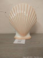 Front view of gloss ceramic vase shaped like a scallop shell with peach and cream tones.