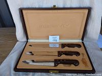 Three Le Gourmet-Chef knives with wooden handles in a velvet-lined case showing the full set.