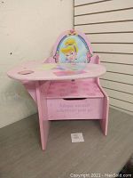 Front angled photo of the pink kid's desk featuring Cinderella artwork on the backrest and a pink drawer with text 'Magic awaits wherever you go', showing shape and structure.