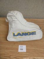 White Lange branded figure skate carrying case with shoulder strap shown closed, logo visible on side.