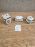 Photo of three milk glass trinket boxes: square box with lid, rectangular box, round footed box with floral design