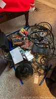 Overhead view of consoles, cables, controllers, games and joystick spread on carpet
