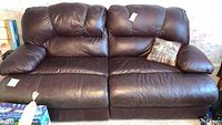 Frontal view of dark brown leather couch with cushion on right side and visible stitching, shows seating and backrest design