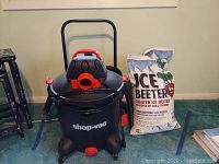 Shop Vac and two bags of ice melter placed on carpeted floor, showing overall lot contents