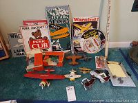 Overall lot on carpet showing metal signs, model airplanes, toy parts and circular tray