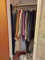 Photo of assorted women's coats hanging in closet, showing various colors and materials.