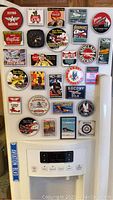 Full view of approximately 29 different aviation themed collectible magnets arranged on a white fridge door with aviation logos and vintage advertisements.