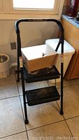 Black Werner two-step platform stool with nonslip tread and supporting frame
