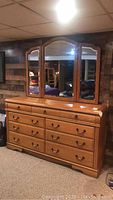 Front view of dresser with attached three-panel arched mirror against wood-paneled wall