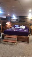 Full view of king bed frame with purple bedding and two under-bed drawers in basement setting