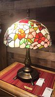 Full view of Tiffany style stained glass lamp showing floral and butterfly patterned shade and bronze-colored base.