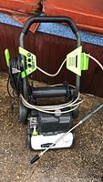Full view of Greenworks electric pressure washer showing coiled black cable, handle, and wheels.