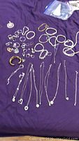 Full overview of necklaces, bracelets, earrings and pendants on purple cloth