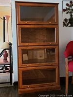 Front view of the wooden barrister cabinet featuring four separate glass-door shelving sections.