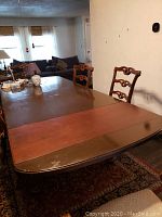 Dining table angled showing surface with two color mismatch leaves and surface wear.