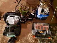 View of entire lot showing Air Dragon compressor, Black & Decker rotary tool case, Ryobi charger, and bins of extension cords.