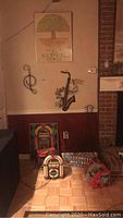Photo showing the musical wall art, framed poster, cassette player, M&M dispensers, and wall signs grouped together in a corner near a fireplace.
