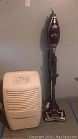 Whirlpool dehumidifier and Shark upright vacuum against wall