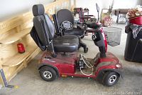 Side view of red Invacare Comet ACC250 mobility scooter with black seat and basket