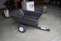 Angled side view of the Yard Commander trailer showing plastic tub and metal frame in garage.