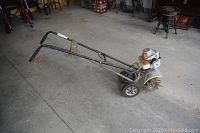 Side view of entire rototiller on concrete floor