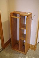 Front angle view of the wooden open storage locker showing compartments and metal hooks.