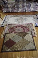 All three rugs stacked visually for size comparison on wooden floor by floral sofa.