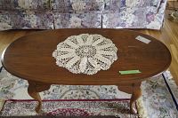 Top-down view of the Sklar Peppler coffee table with a doily placed on top showing wood grain and some surface wear.