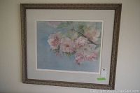 Framed print of pink flowers on branches with green leaves on light blue background, showing overall artwork and frame.