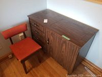Wooden sewing table and chair set with fabric seat and back, placed in corner