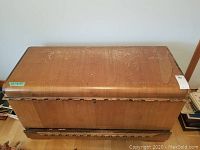 Front view of the large rectangular wooden chest showing surface wear and some discoloration on the top.