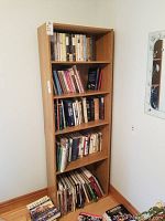 Front view of the wooden bookcase filled with books for staging only, to be sold without contents as per description.
