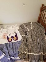 19th century historical replica dress, apron, slippers, and moccasins laid out on bed