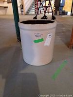 Five-gallon beige stoneware crock with Blue Crown logo and marks on outer surface, shown with auction lot tags
