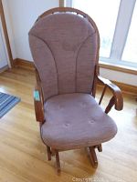 Front view of slider rocking chair showing padded fabric seat and backrest with button tufting, wooden armrests and base