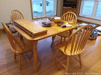 Full view of wood kitchen table with two inserts and four matching wood chairs. Contents on table not included.
