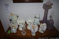 Collection arranged on wooden table showing all figurines, vase, bell, and cat figurine