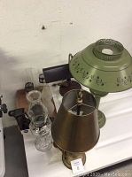 Overview of lamps grouped together showing the green floral metal lamp, brass lamp, and adjustable desk lamp.